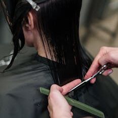 Close-up of a hairstylist cutting a woman's hair in a salon, showcasing precise techniques.